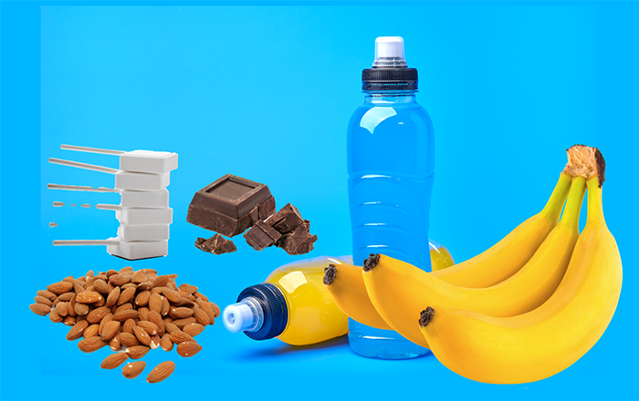 Une sélection d'aliments pour la récupération après l'effort comprenant des amandes, du chocolat noir, des bananes, des boissons énergétiques, et des recharges de glycogène.