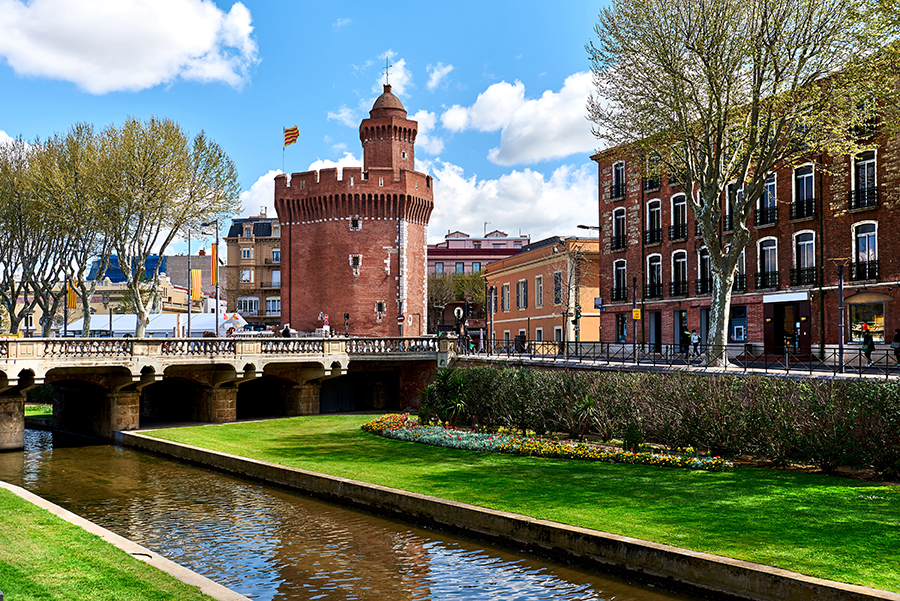 Château de Perpignan et canal entouré de verdure par une journée ensoleillée, symbole de la ville où se déroulent les activités de La Fistinière