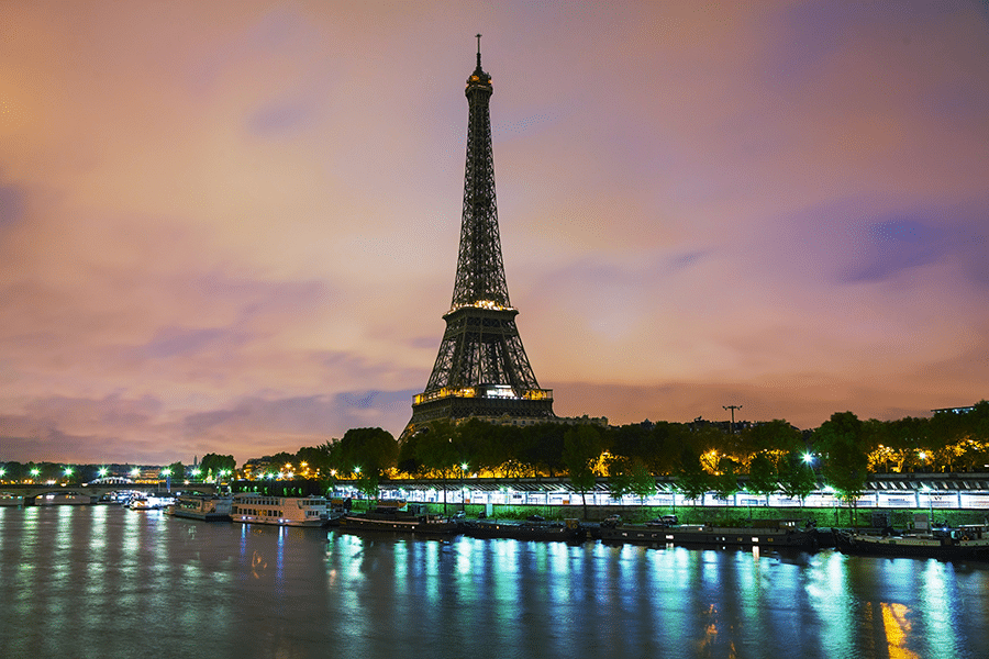 Photo de la Tour Eiffel illuminée au crépuscule, vue depuis la Seine à Paris; Représente les activités de La Fistinière à Paris